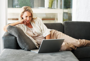 Portrait of a pretty relaxed middle aged woman using laptop on couch