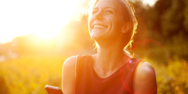 A woman smiling and looking up at the sky.